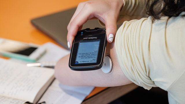 A person living with diabetes using technology to manage their condition