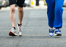 2 pairs of legs and feet jogging along tarmac