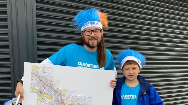 A man and a boy are wearing Diabetes UK tshirts and crazy hair, holding a map.