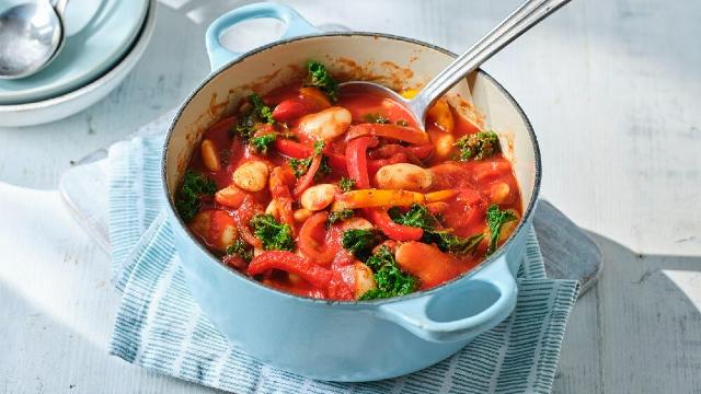 Bowl of tomato, garlic and butterbean stew sits on top of tea towel