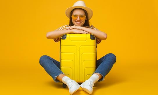 young traveller hugging yellow suitcase